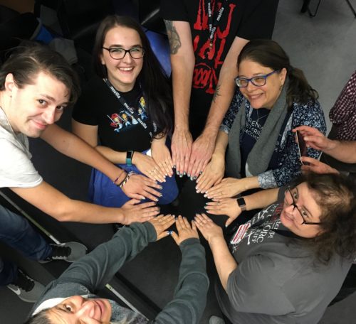 A circle of people showing their painted nails and looking at the camera